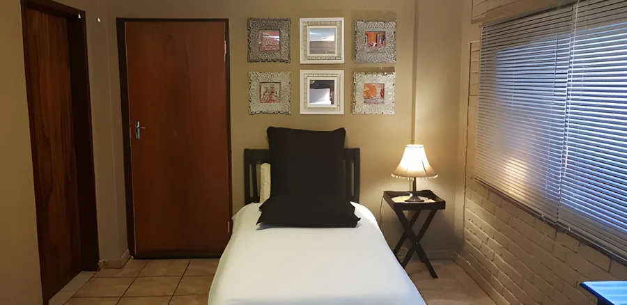A single guest room with a wooden door and framed art above the bed