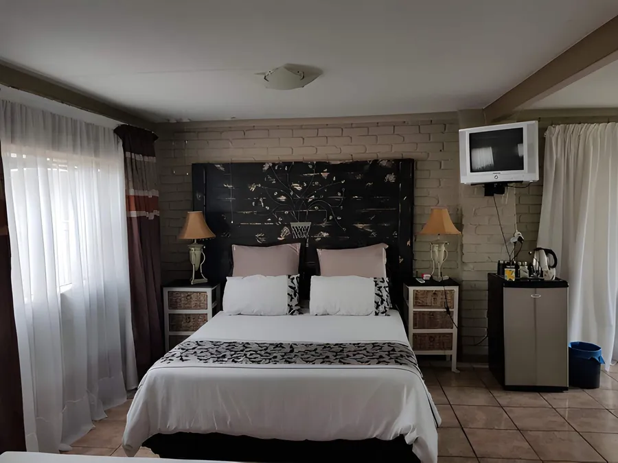 A double room with white bedding, a wooden headboard and a television